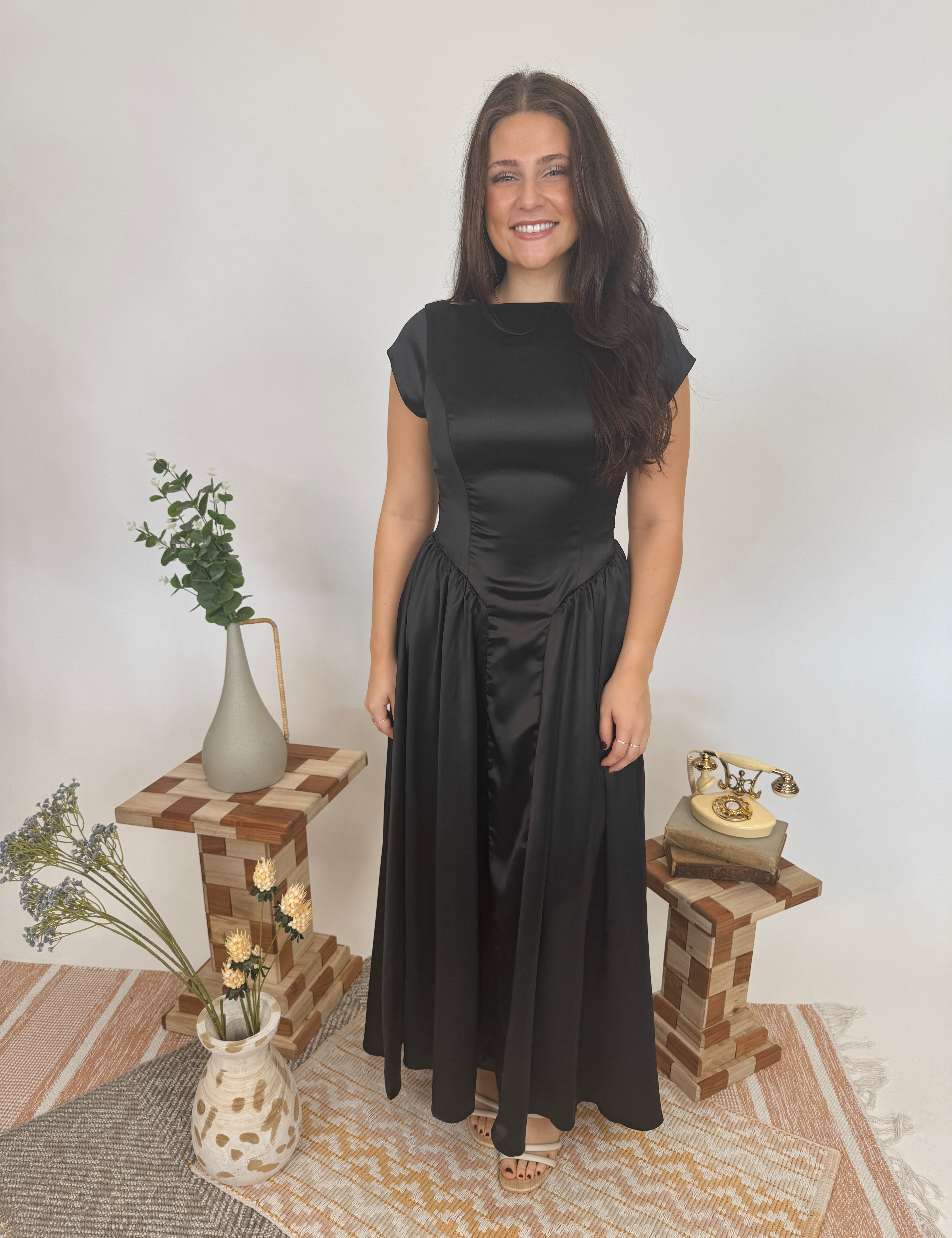 Woman in a black dress standing in a room with decorative elements.