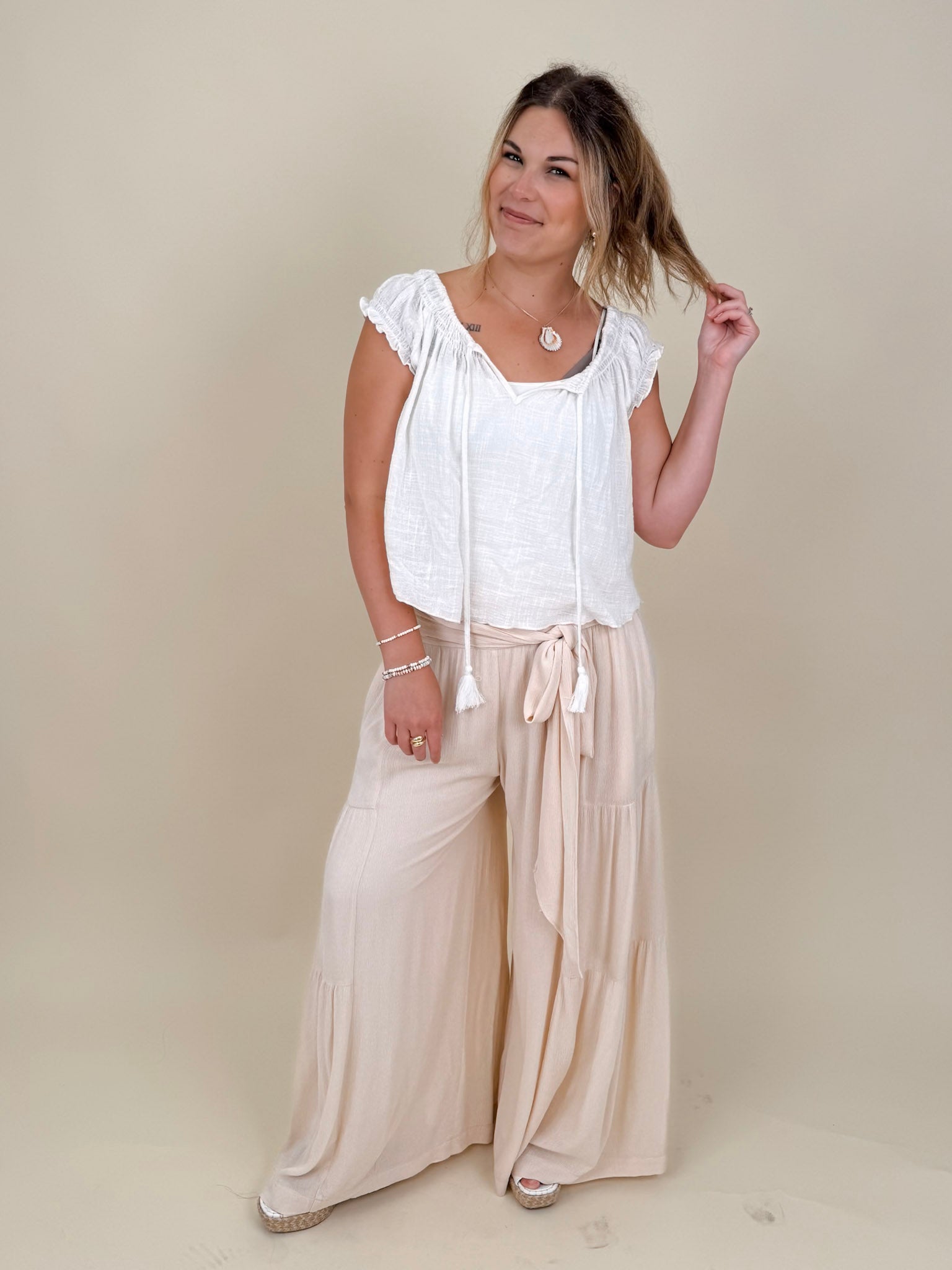 Evanthe Tie-Waist Wide Leg Pants in cream with tiered wide-leg and tassel tie — Paper Doll