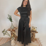 Woman in a black dress standing in a room with decorative elements.