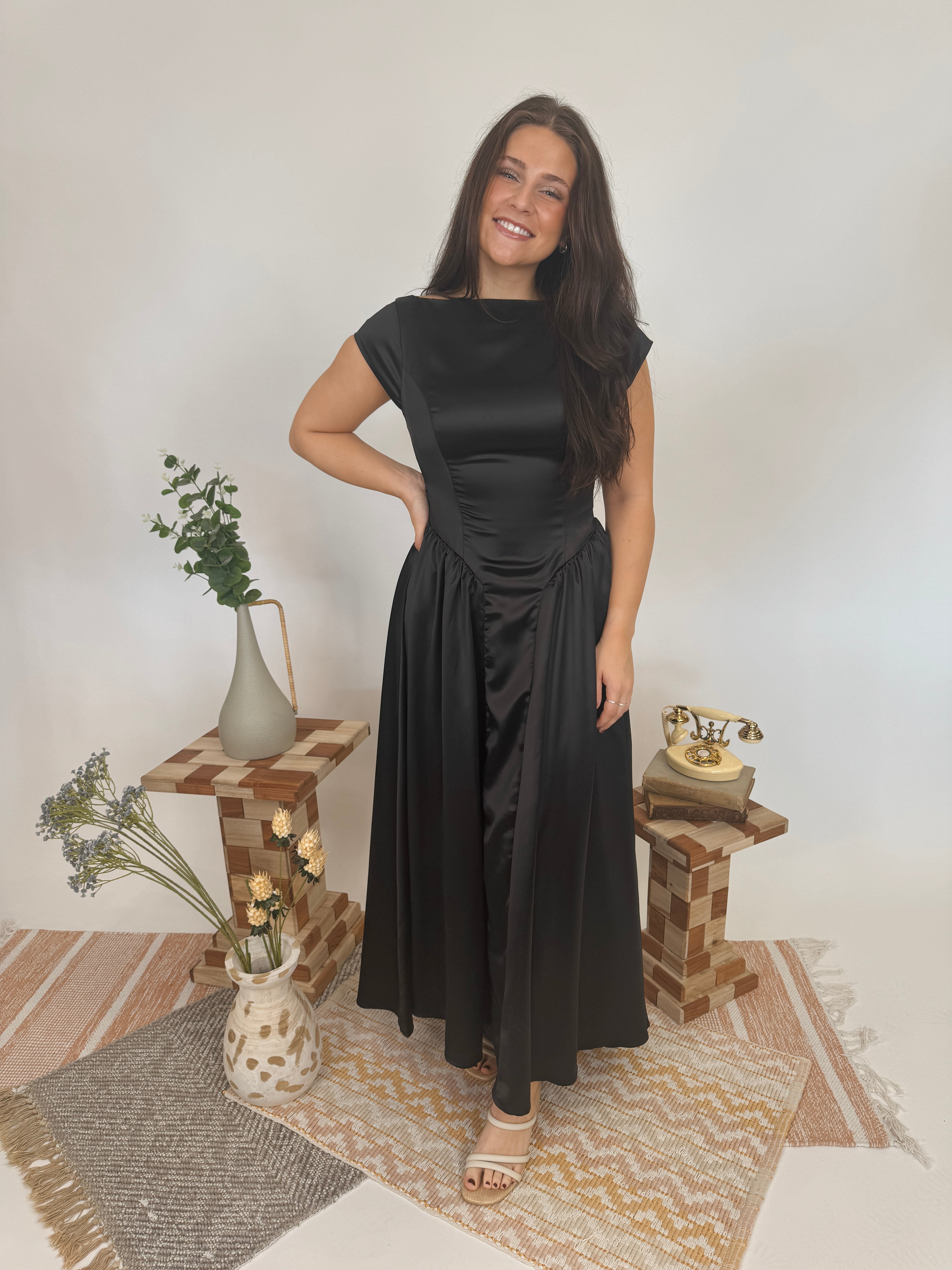 Woman in a black dress standing in a room with decorative elements.