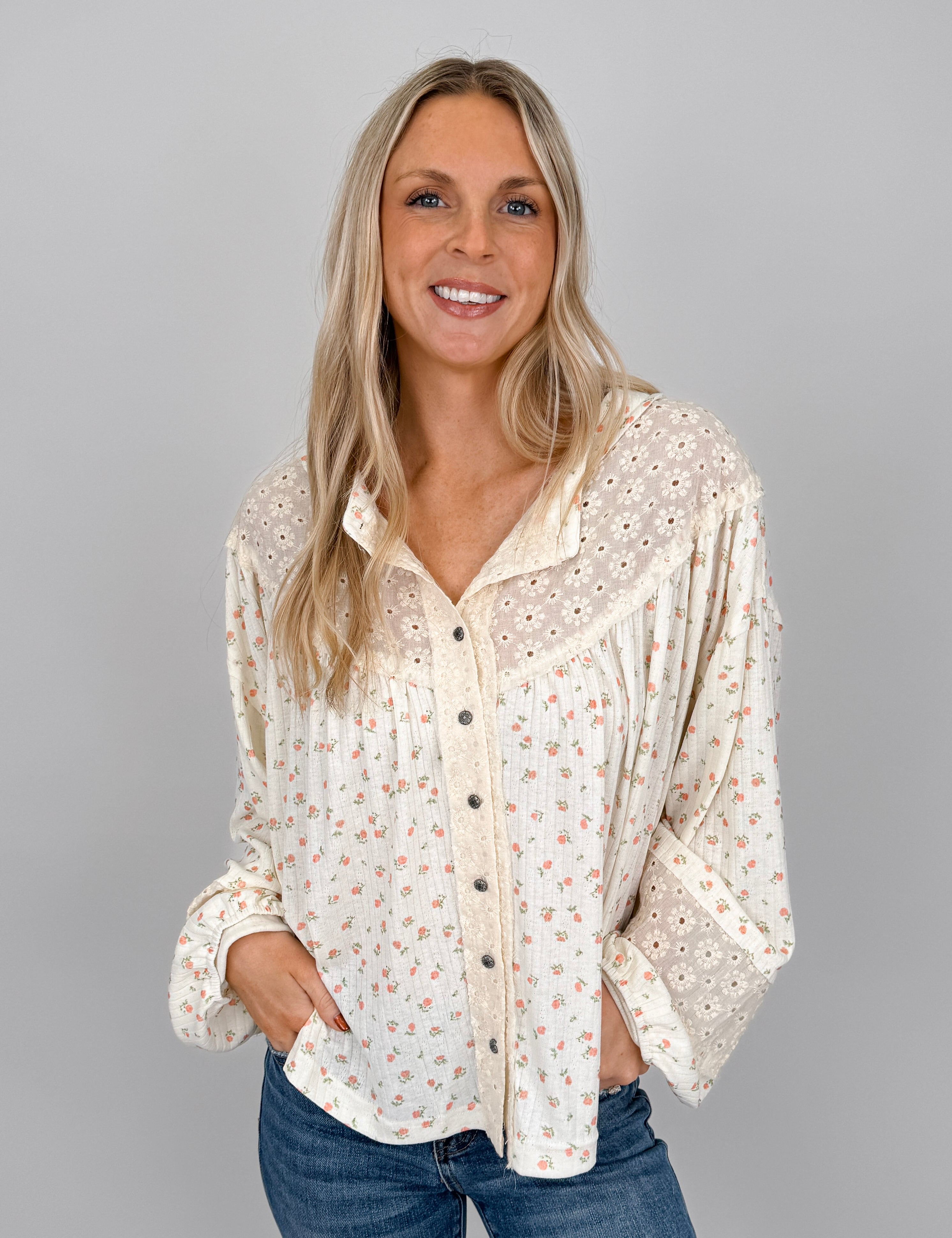 Woman wearing cream Small Town Girl Knit Top with ditsy floral print, eyelet lace yoke detail, button-front placket, and ruffle cuffs