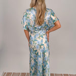 Woman wearing cream Marigold Maxi Dress with blue hydrangea floral print, twisted front waist detail, kimono sleeves, and V-neckline