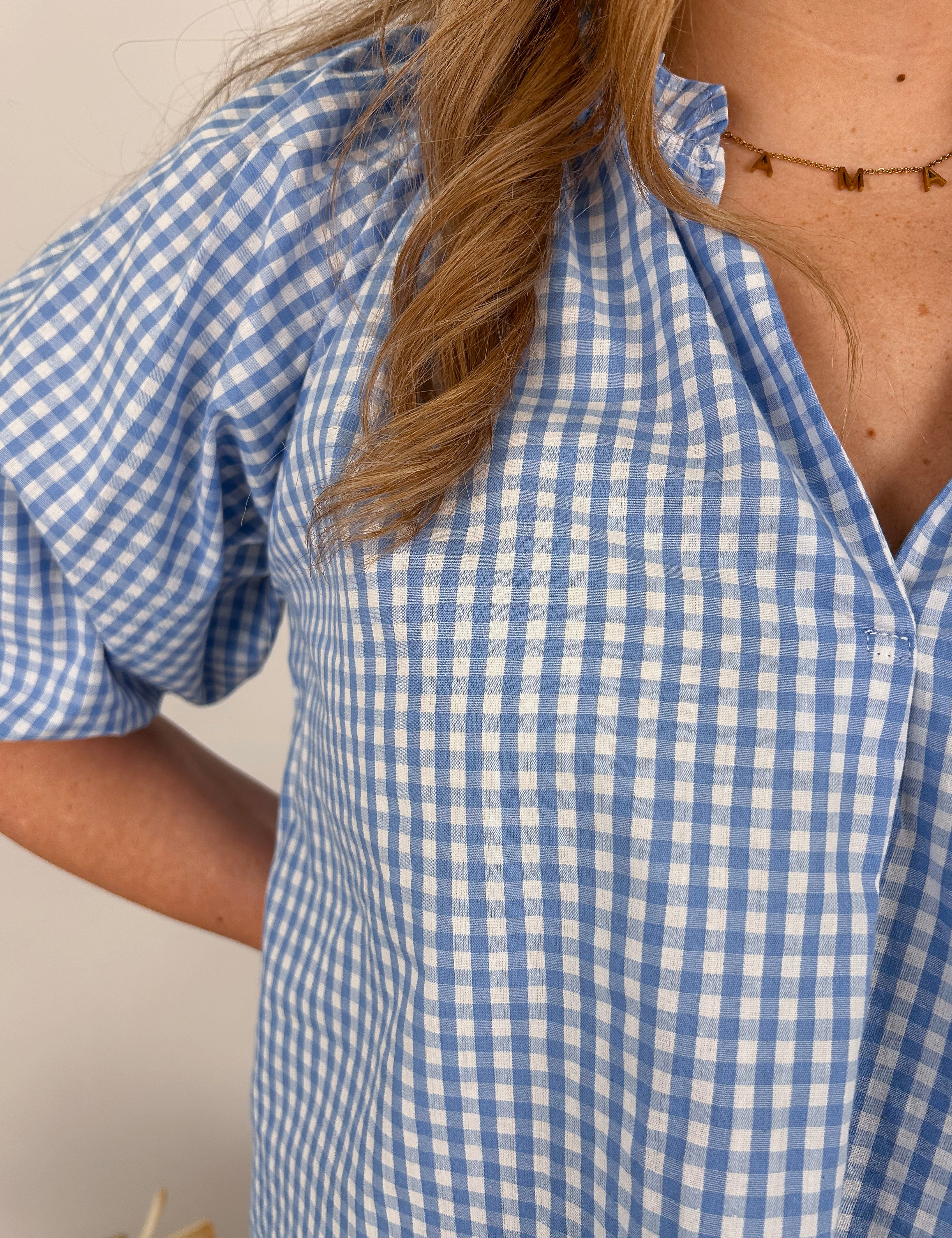 Woman wearing blue and white gingham Kansas Anymore Blouse with puff sleeves, V-neckline, and relaxed fit in 100% cotton