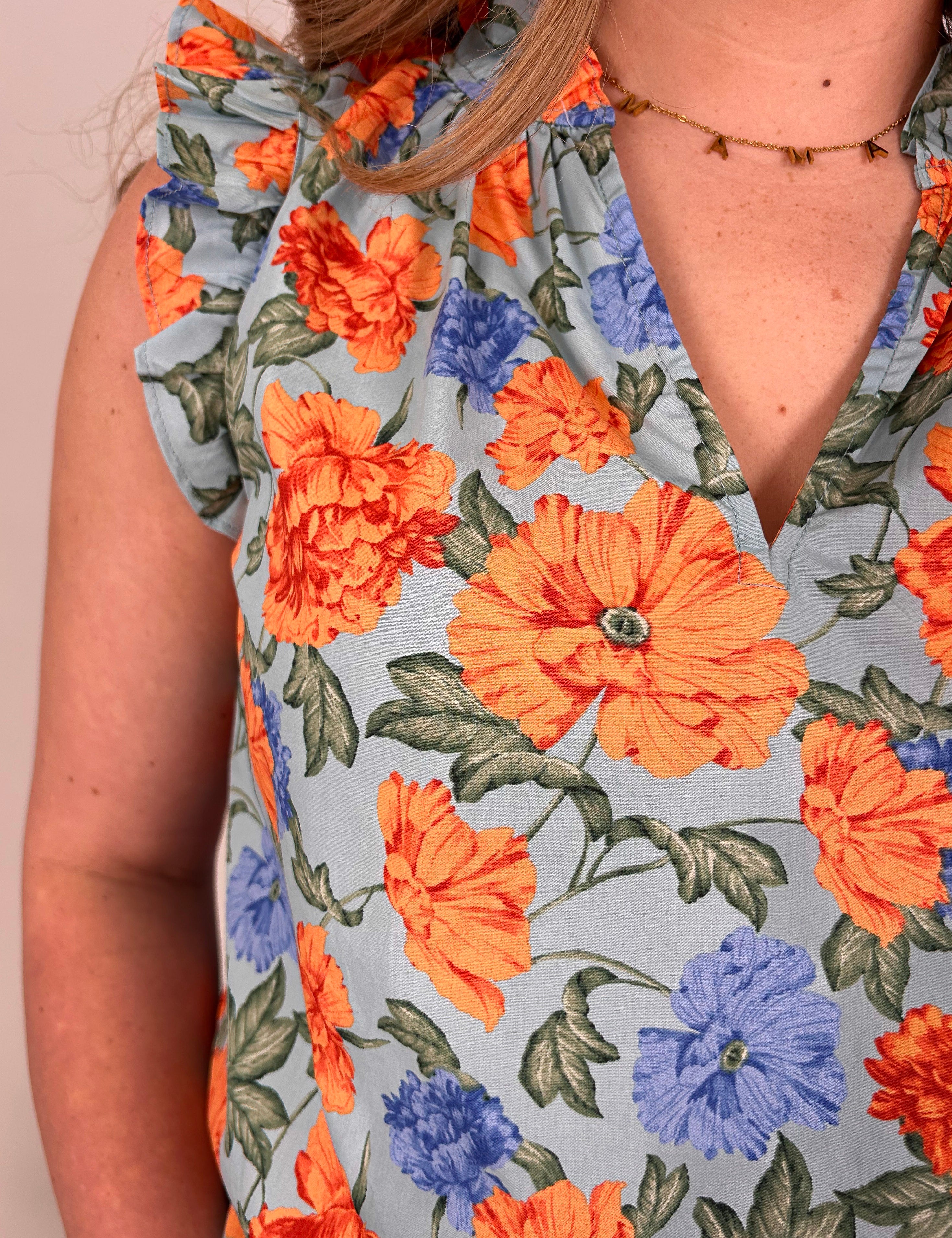 Close-up of a floral dress with orange and blue flowers on a light background