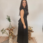 Woman in a black dress standing in a room with decorative elements.