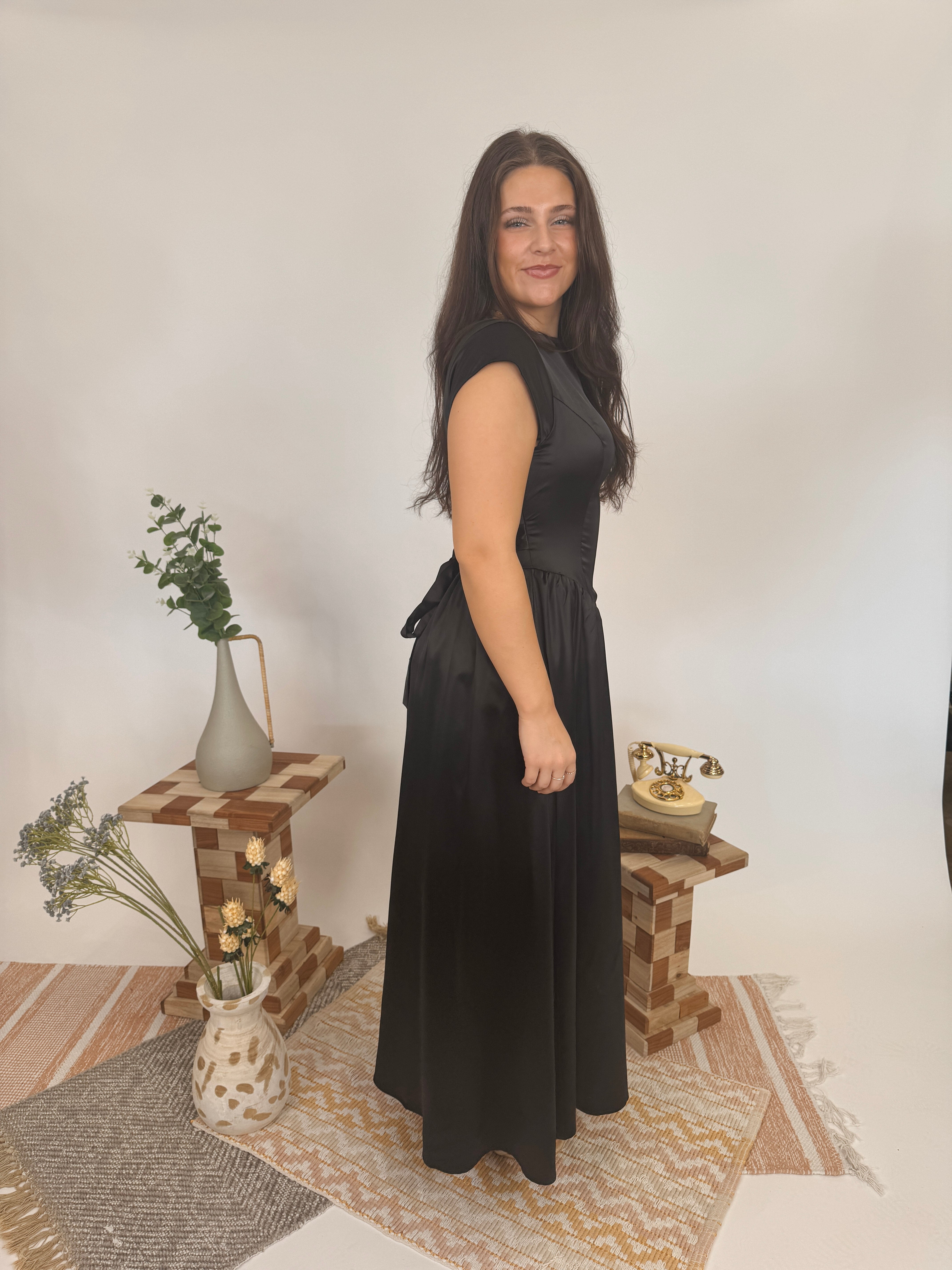Woman in a black dress standing in a room with decorative elements.