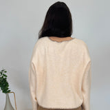 Person wearing a beige sweater and brown pants standing in a room with decorative elements.