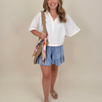 Kira Smocked Shorts in light denim blue with smocked waist and tiered ruffle hem — Paper Doll