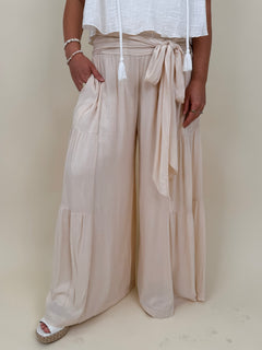 Evanthe Tie-Waist Wide Leg Pants in cream with tiered wide-leg and tassel tie — Paper Doll