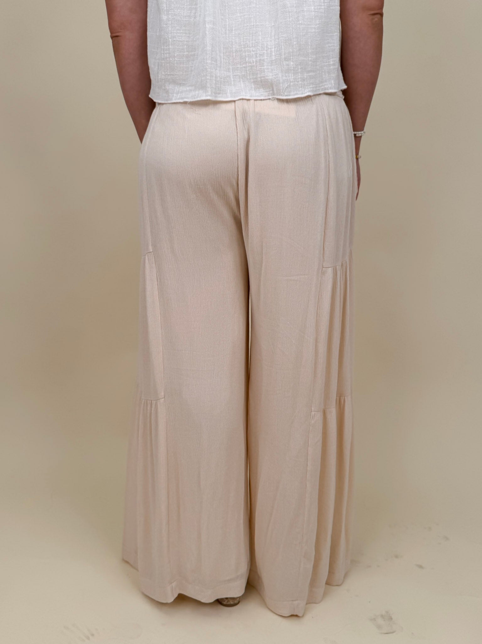 Evanthe Tie-Waist Wide Leg Pants in cream with tiered wide-leg and tassel tie — Paper Doll