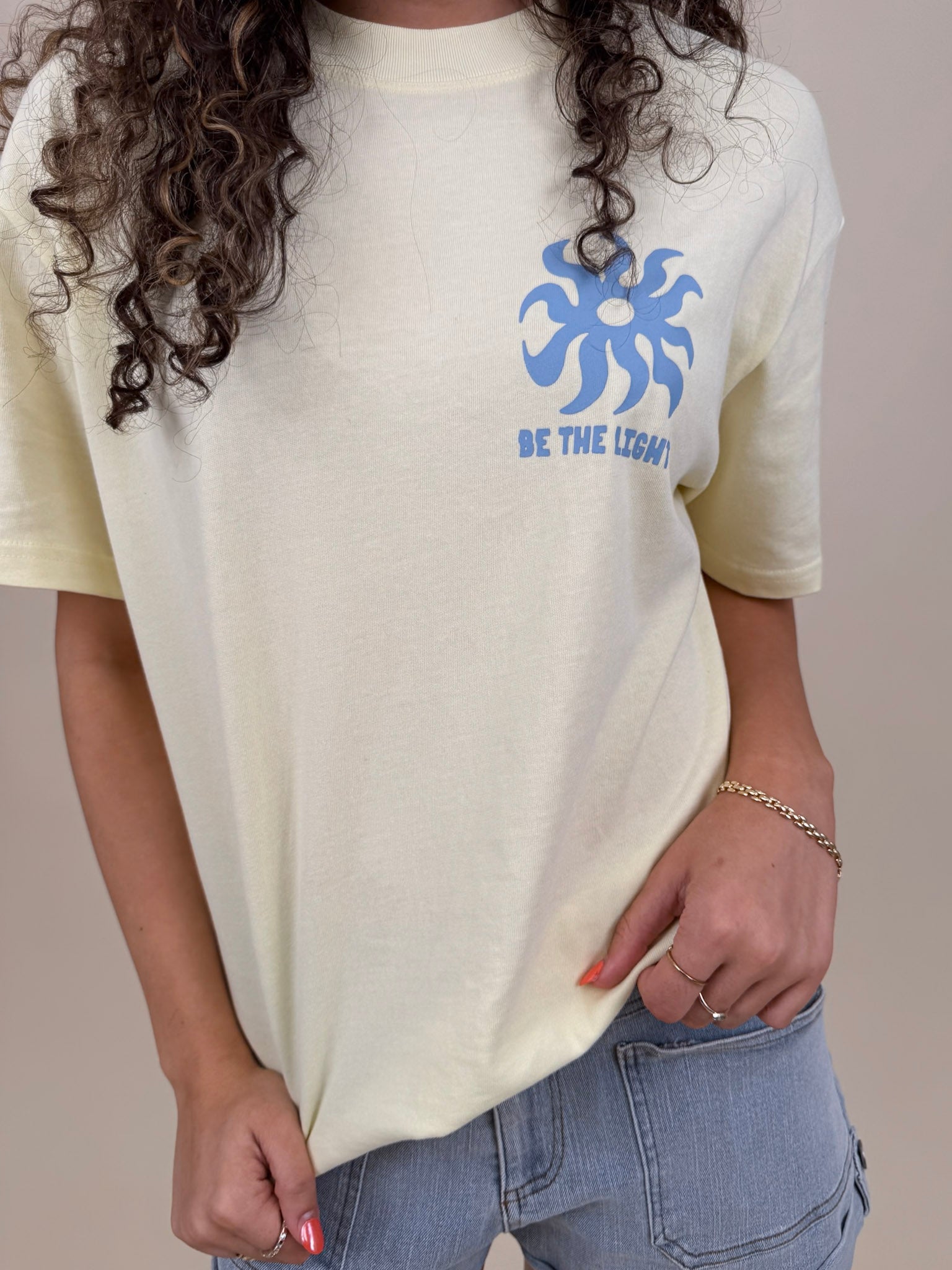 Be the Light Unisex Tee in butter yellow with blue sun graphic and statement text — Paper Doll
