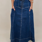 Belhaven Skirt in dark wash denim with a corset style lace up front, deep patch pockets, seamed panels, and a full sweeping maxi length