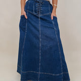 Belhaven Skirt in dark wash denim with a corset style lace up front, deep patch pockets, seamed panels, and a full sweeping maxi length