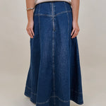 Belhaven Skirt in dark wash denim with a corset style lace up front, deep patch pockets, seamed panels, and a full sweeping maxi length