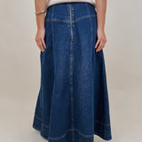 Belhaven Skirt in dark wash denim with a corset style lace up front, deep patch pockets, seamed panels, and a full sweeping maxi length