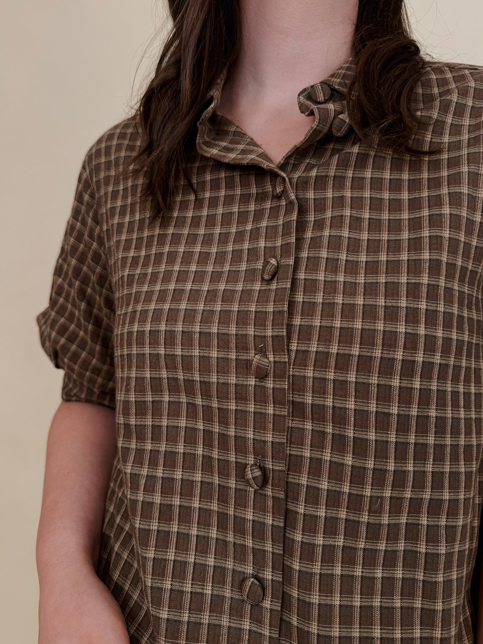 Belle Plaid Button Up Top in chocolate brown and cream windowpane plaid with covered buttons, a ruffled collar, and cuffed short sleeves
