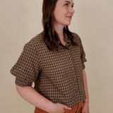 Belle Plaid Button Up Top in chocolate brown and cream windowpane plaid with covered buttons, a ruffled collar, and cuffed short sleeves