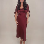 Katrina Midi Dress in olive crinkled satin with lace trim at the sweetheart neckline and empire waist, puff sleeves with bow ties, and a flowing bias cut midi skirt