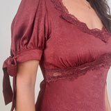 Katrina Midi Dress in burgundy crinkled satin with lace trim at the sweetheart neckline and empire waist, puff sleeves with bow ties, and a flowing bias cut midi skirt