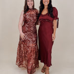 Katrina Midi Dress in burgundy crinkled satin with lace trim at the sweetheart neckline and empire waist, puff sleeves with bow ties, and a flowing bias cut midi skirt