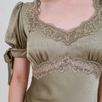 Katrina Midi Dress in olive crinkled satin with lace trim at the sweetheart neckline and empire waist, puff sleeves with bow ties, and a flowing bias cut midi skirt