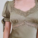 Katrina Midi Dress in olive crinkled satin with lace trim at the sweetheart neckline and empire waist, puff sleeves with bow ties, and a flowing bias cut midi skirt