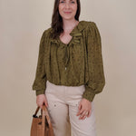 Kortni Blouse in martini olive with tonal brown polka dots, a ruffle collar, tie front V neckline, and balloon sleeves