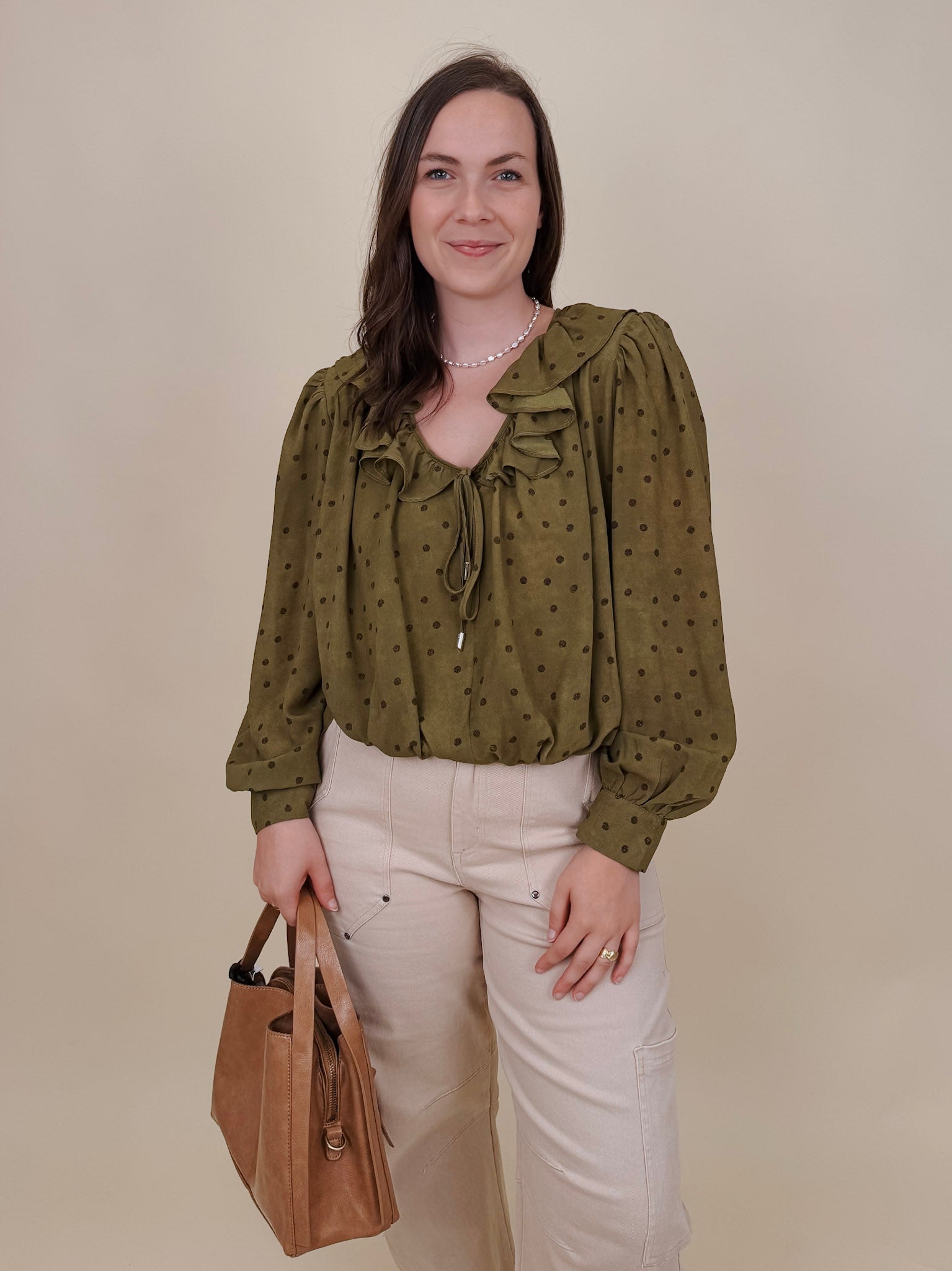 Kortni Blouse in martini olive with tonal brown polka dots, a ruffle collar, tie front V neckline, and balloon sleeves