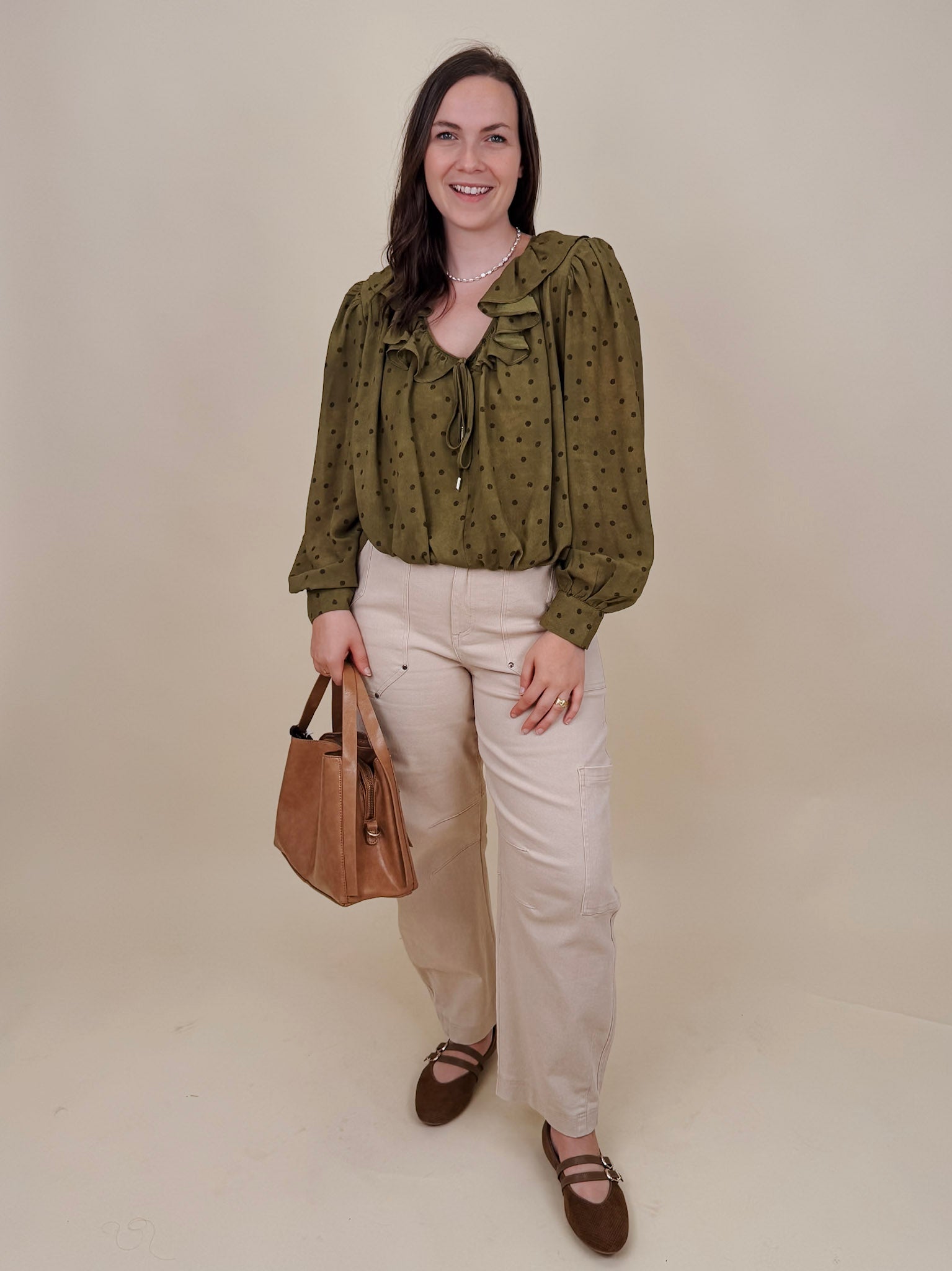 Kortni Blouse in martini olive with tonal brown polka dots, a ruffle collar, tie front V neckline, and balloon sleeves