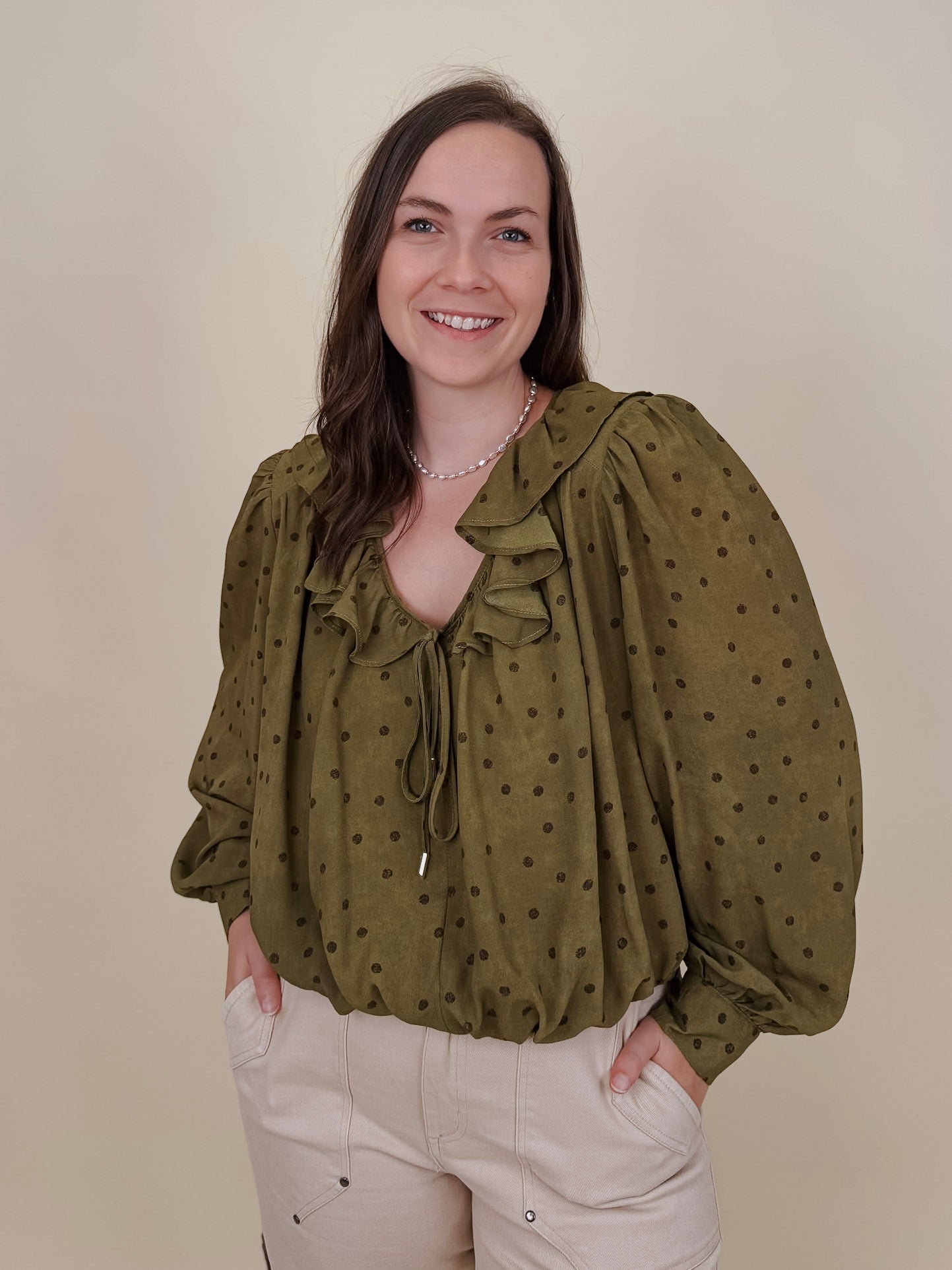 Kortni Blouse in martini olive with tonal brown polka dots, a ruffle collar, tie front V neckline, and balloon sleeves