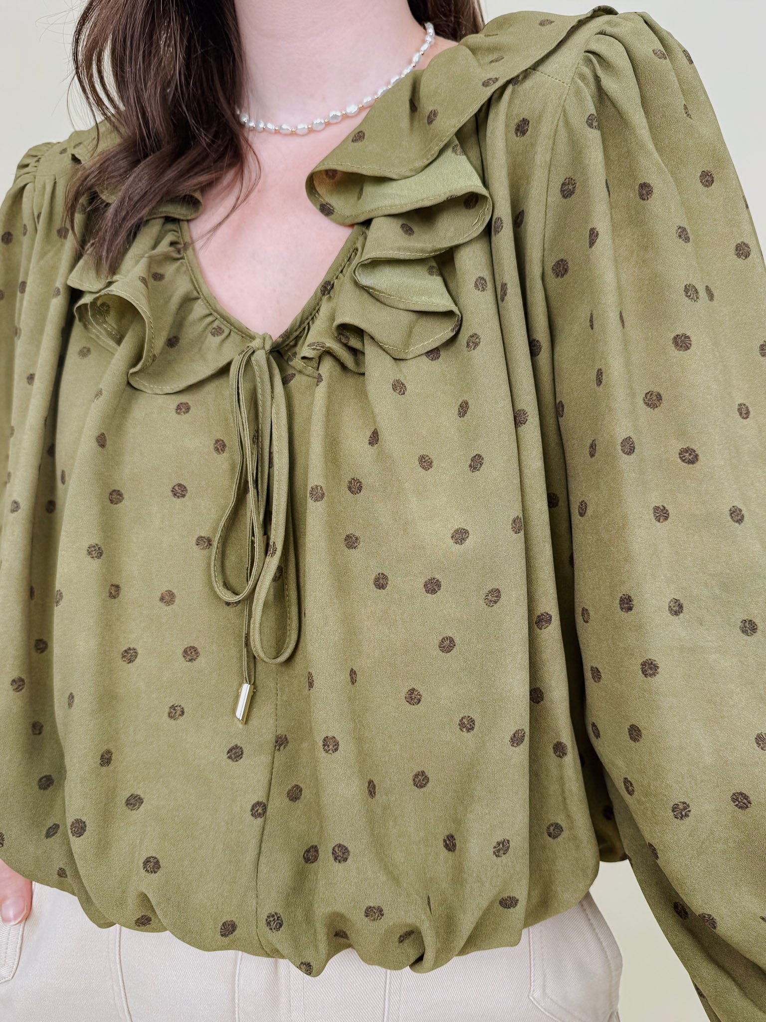 Kortni Blouse in martini olive with tonal brown polka dots, a ruffle collar, tie front V neckline, and balloon sleeves