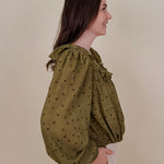 Kortni Blouse in martini olive with tonal brown polka dots, a ruffle collar, tie front V neckline, and balloon sleeves