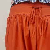 Magazine Street Pant in rust cotton with a smocked drawstring waist, gathered yoke, side pockets, and a full balloon leg