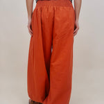 Magazine Street Pant in rust cotton with a smocked drawstring waist, gathered yoke, side pockets, and a full balloon leg