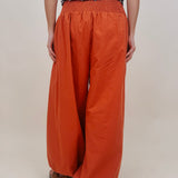 Magazine Street Pant in rust cotton with a smocked drawstring waist, gathered yoke, side pockets, and a full balloon leg