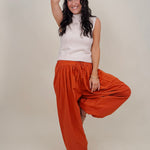 Magazine Street Pant in rust cotton with a smocked drawstring waist, gathered yoke, side pockets, and a full balloon leg
