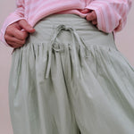 Magazine Street Pant in light olive cotton with a smocked drawstring waist, gathered yoke, side pockets, and a full balloon leg