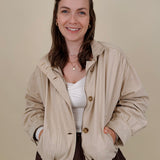 Pumpkin Patch Denim Jacket in soft beige with tortoise buttons over a hidden zip front, gathered shoulders, welt pockets, and an elastic bubble hem