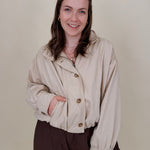 Pumpkin Patch Denim Jacket in soft beige with tortoise buttons over a hidden zip front, gathered shoulders, welt pockets, and an elastic bubble hem