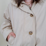 Pumpkin Patch Denim Jacket in soft beige with tortoise buttons over a hidden zip front, gathered shoulders, welt pockets, and an elastic bubble hem