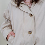 Pumpkin Patch Denim Jacket in soft beige with tortoise buttons over a hidden zip front, gathered shoulders, welt pockets, and an elastic bubble hem