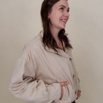 Pumpkin Patch Denim Jacket in soft beige with tortoise buttons over a hidden zip front, gathered shoulders, welt pockets, and an elastic bubble hem