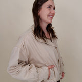 Pumpkin Patch Denim Jacket in soft beige with tortoise buttons over a hidden zip front, gathered shoulders, welt pockets, and an elastic bubble hem
