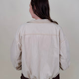 Pumpkin Patch Denim Jacket in soft beige with tortoise buttons over a hidden zip front, gathered shoulders, welt pockets, and an elastic bubble hem