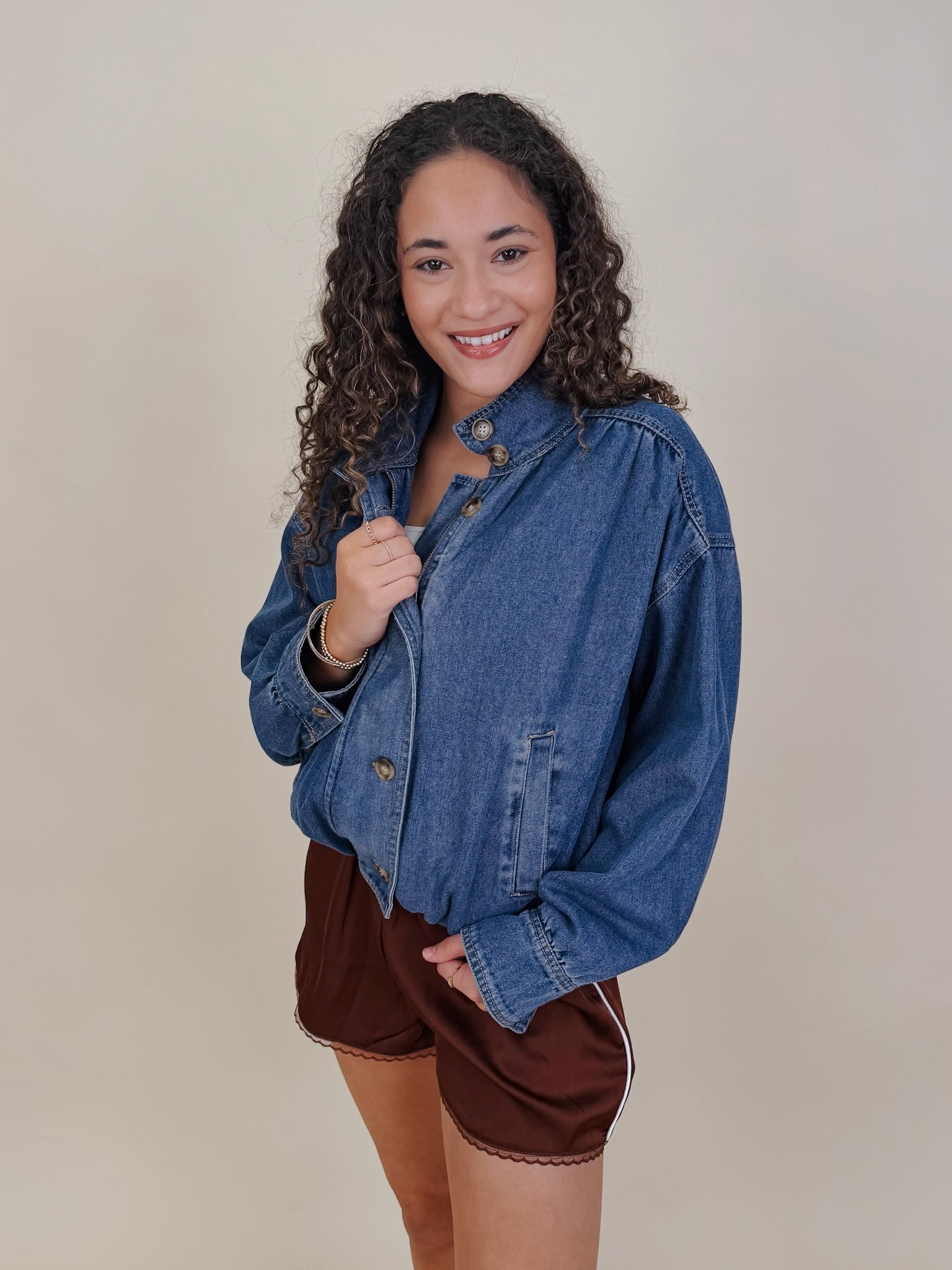 Pumpkin Patch Denim Jacket in medium wash denim with tortoise buttons over a hidden zip front, gathered shoulders, welt pockets, and an elastic bubble hem