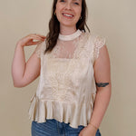 So Long London Blouse in champagne satin with eyelash lace panels, a mock neckline, cap sleeves, and a ruffled peplum hem with a ribbon tie back