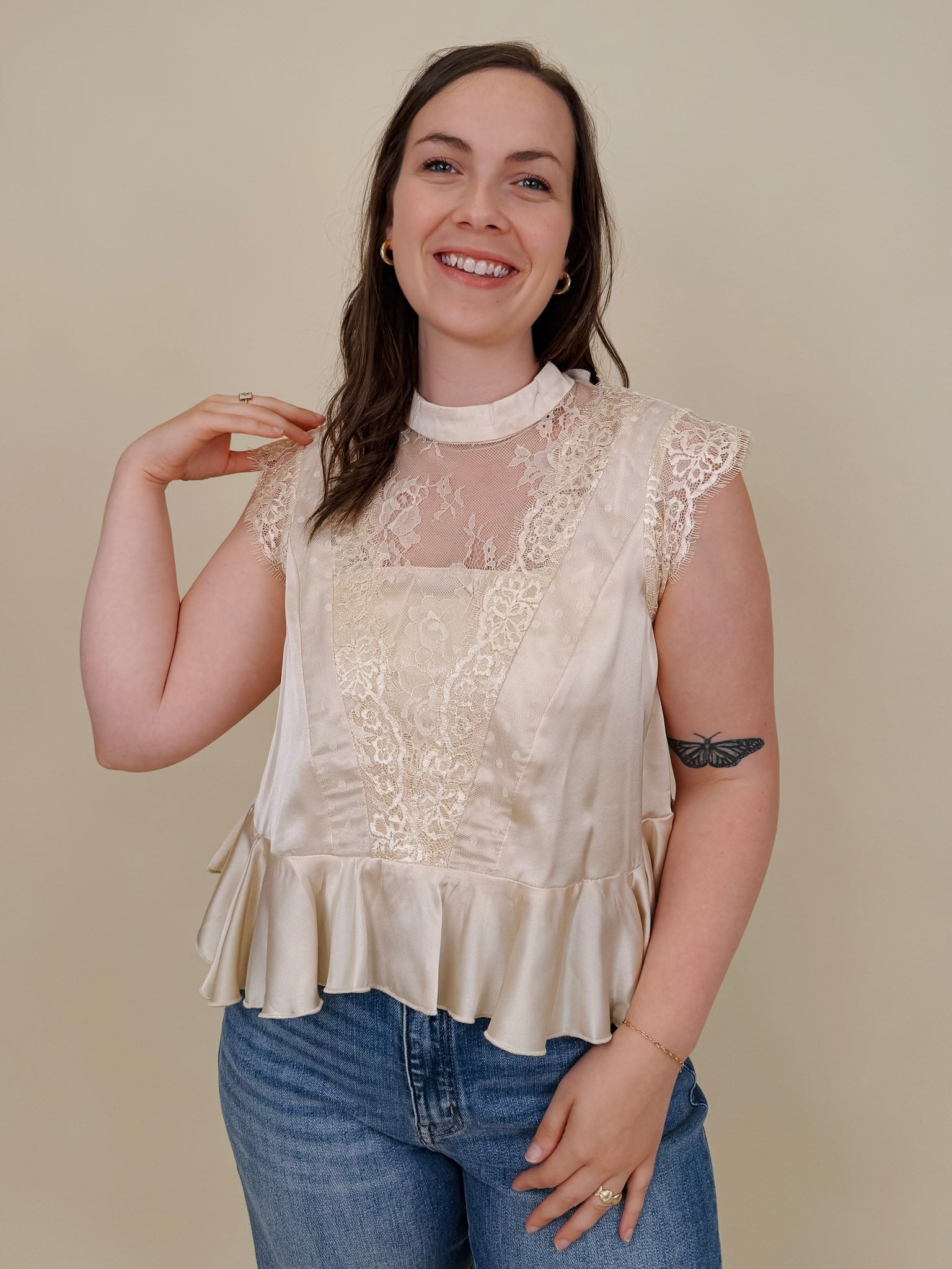So Long London Blouse in champagne satin with eyelash lace panels, a mock neckline, cap sleeves, and a ruffled peplum hem with a ribbon tie back