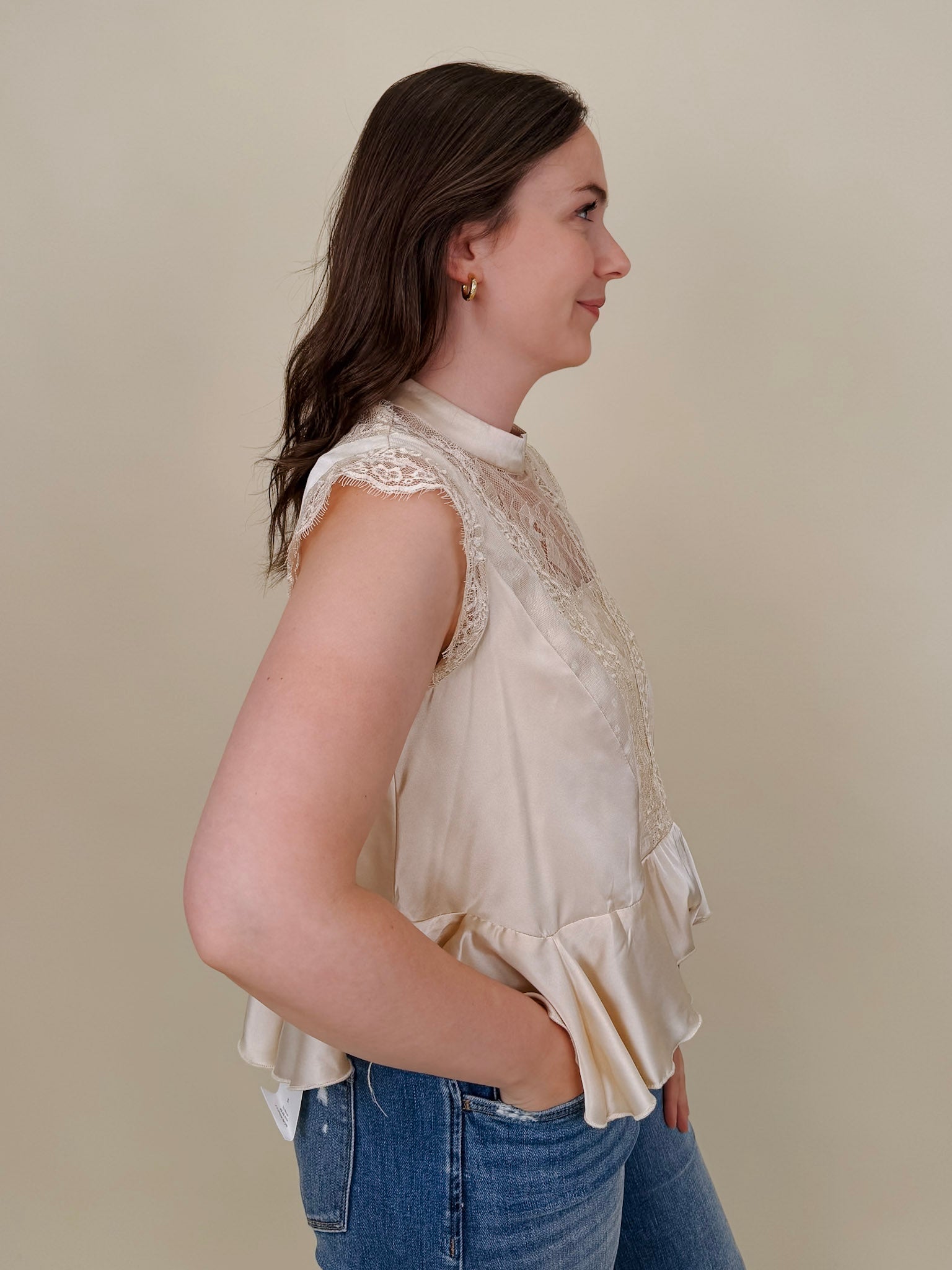 So Long London Blouse in champagne satin with eyelash lace panels, a mock neckline, cap sleeves, and a ruffled peplum hem with a ribbon tie back