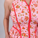 Tara Dress in pink ditsy floral print with red contrast piping, halter V neckline, fitted bodice, and full gathered midi skirt