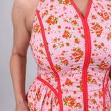 Tara Dress in pink ditsy floral print with red contrast piping, halter V neckline, fitted bodice, and full gathered midi skirt